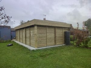 Abri de jardin en bois avec pelouse et robot tondeuse.