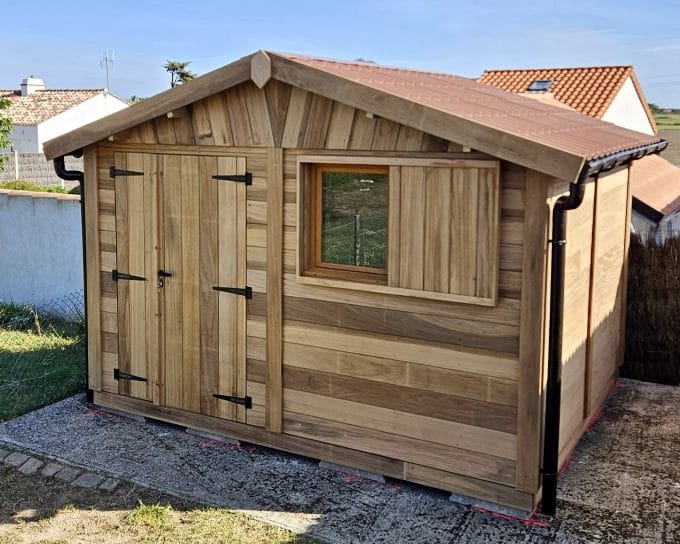 Abri de jardin en bois neuf, toiture cuivre, ciel bleu.