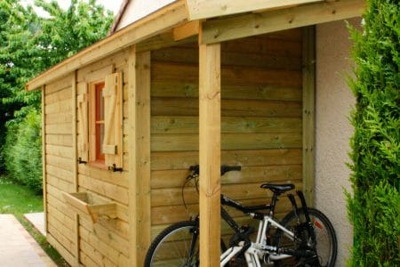 Abri de jardin en bois avec auvent et vélo.