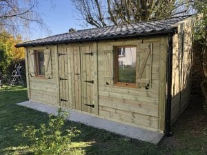 Abri de jardin en bois neuf, toit tuilé, jour ensoleillé.