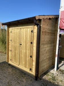 Abri de jardin en bois avec gouttière sous ciel bleu.