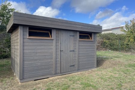 Abri de jardin moderne en bois gris avec fenêtres et porte.