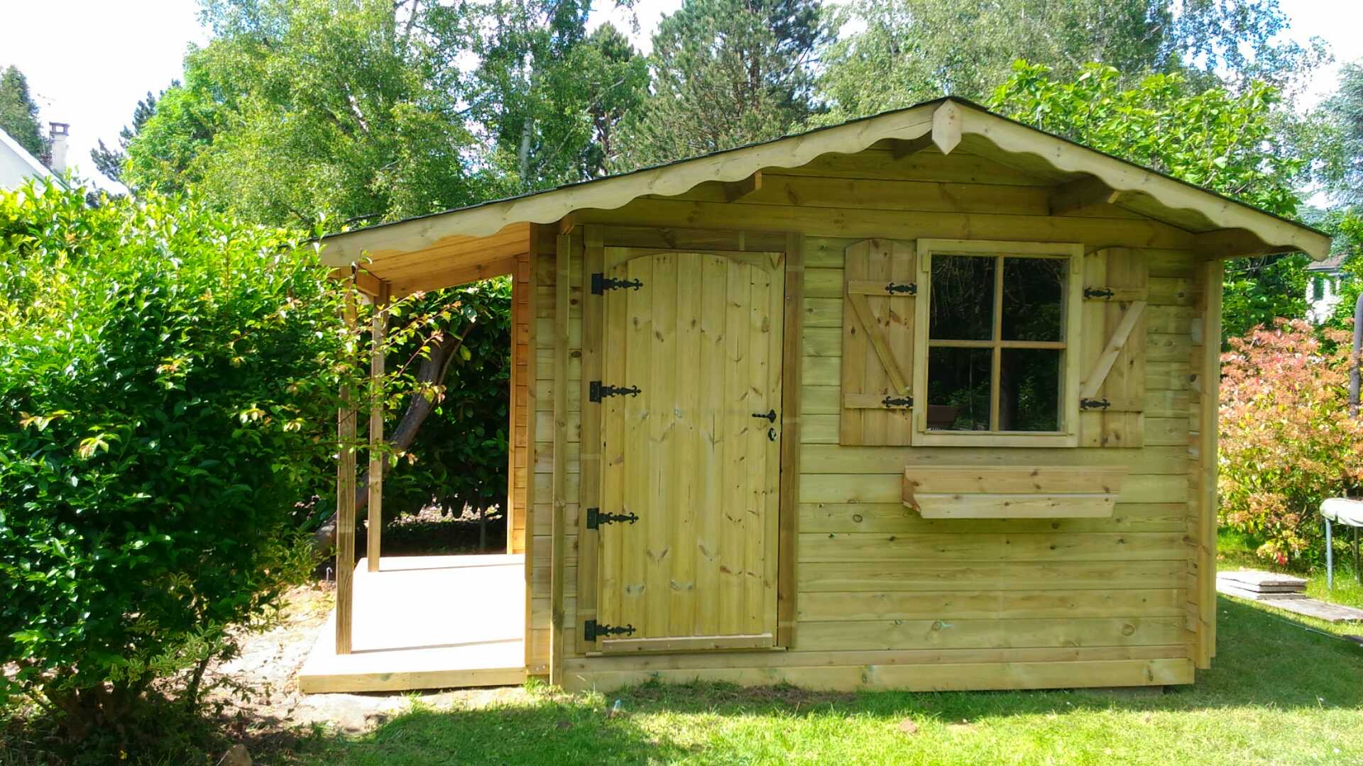 Abri de jardin en bois avec porche et fenêtre.