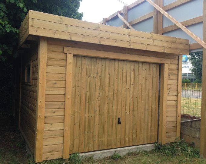Garage en bois clair, porte fermée, toit plat.