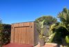 Abri de jardin moderne en bois, plantes tropicales, ciel bleu.