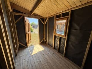 Intérieur cabane bois, porte et fenêtre, lumière naturelle.